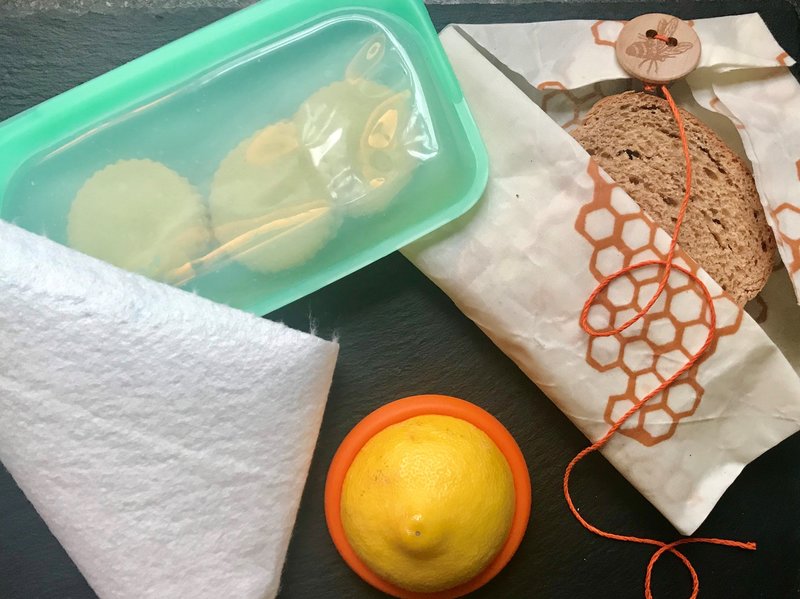 Last year, the author set about reducing her reliance on single-use disposables in the kitchen. Above are some of the tools she has adopted for food storage: a heavy-duty reusable silicone zip-top bag, bamboo towels, silicone disks that slip over the ends of cut pieces of fruits and vegetables, and beeswax-covered fabrics. CREDIT: Kristen Hartke for NPR