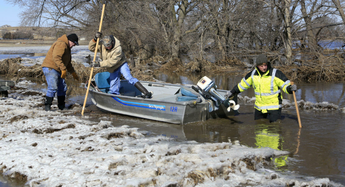 Tom Wilke, his son Chad, and Nick Kenny launch a boat into the swollen waters of the Elkhorn River to check on Wilke's flooded property, in Norfolk, Neb., on Friday, March 15. Nati Harnik/AP