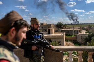 U.S.-backed fighters stand guard on a building during shelling of the Islamic State's last holdout in the town of Baghouz, Syria, on March 3. Bulent Kilic/AFP/Getty Images