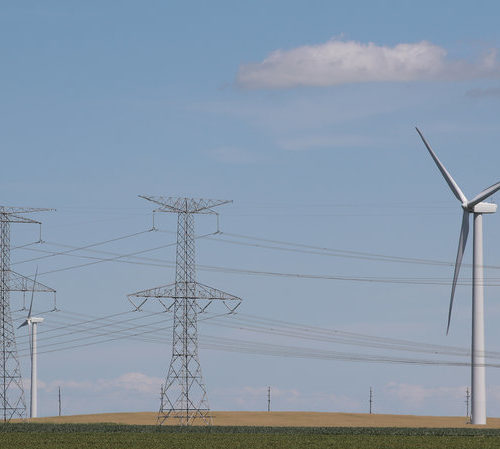 Power lines and power-generating windmills rise above the rural landscape on June 13, 2018, near Dwight, Ill. Driven by falling costs, global spending on renewable energy sources like wind and solar is now outpacing investment in electricity from fossil fuels and nuclear power. CREDIT: SCOTT OLSON/GETTY IMAGES