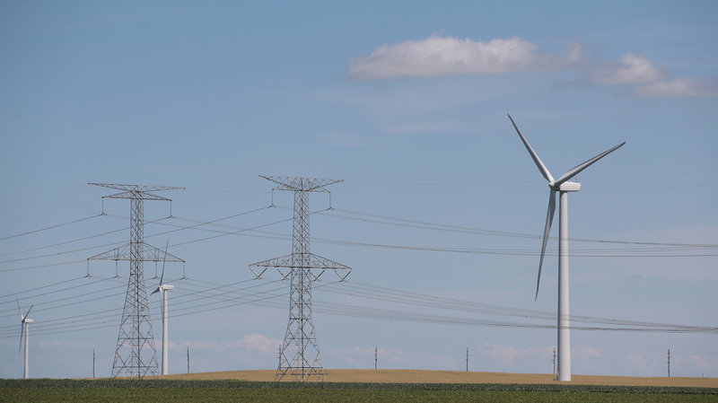 Power lines and power-generating windmills rise above the rural landscape on June 13, 2018, near Dwight, Ill. Driven by falling costs, global spending on renewable energy sources like wind and solar is now outpacing investment in electricity from fossil fuels and nuclear power. CREDIT: SCOTT OLSON/GETTY IMAGES
