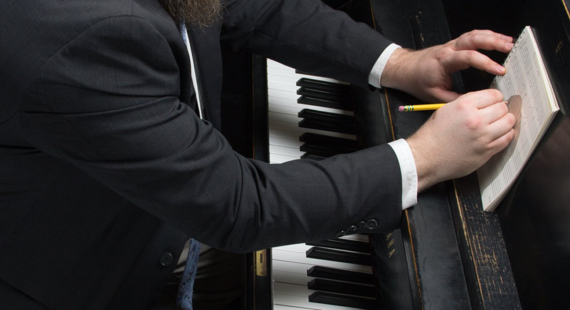 composer sitting at piano