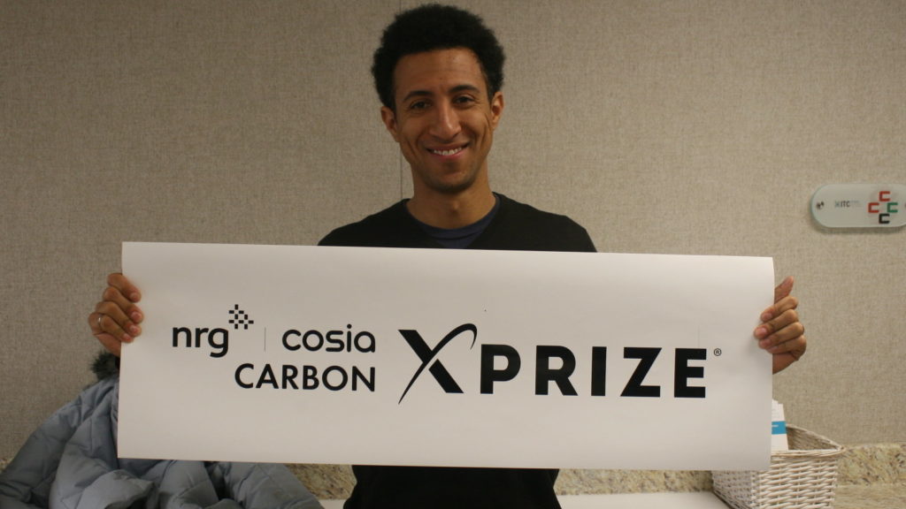 Marcius Extavour, executive director of NRG COSIA Carbon XPRIZE holding up a banner inside the Integrated Test Center in Gillette, Wyo. CREDIT: COOPER MCKIM/WYOMING PUBLIC RADIO