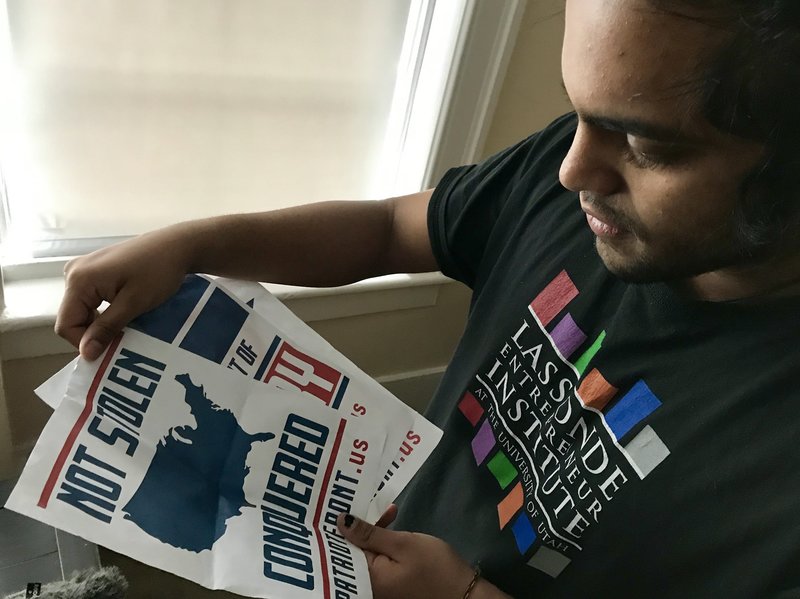 Mohan Sudabattula, a senior at the University of Utah, shows posters he found on campus from the white nationalist group Patriot Front. CREDIT: NATE HEGYI/KUER