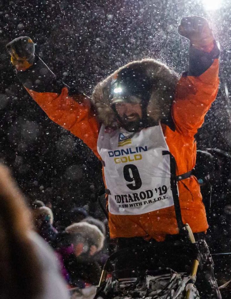 Peter Kaiser celebrates his first-place victory at the finish line of the Iditarod race. Courtesy of John Wallace