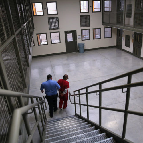A guard escorts a detained immigrant from his "segregation cell" back into the general population at the Adelanto Detention Facility in November 2013. Today the privately run ICE facility in Adelanto, Calif., houses nearly 2,000 men and women and has come under sharp criticism by the California attorney general and other investigators for health and safety problems. CREDIT: John Moore/Getty Images