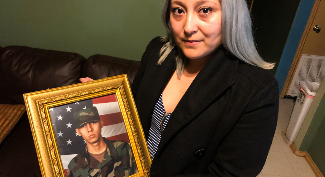 Edgar Baltazar Garcia's wife, Jennifer Garcia, holds a photo of her husband from when he was deployed at Balad Air Base in Iraq as a turret gunner in a Humvee. He now faces deportation to Mexico over a felony conviction. John Burnett/NPR