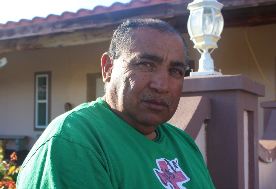 Sergio Rodriguez sits in the warm spring sunlight outside of the Our Lady of the Desert Parish catholic church in Mattawa, in central Washington. He says the workers help raise local wages about a dollar when they come to town, but they also get to take more of their paycheck home. CREDIT: ESMY JIMENEZ/KUOW