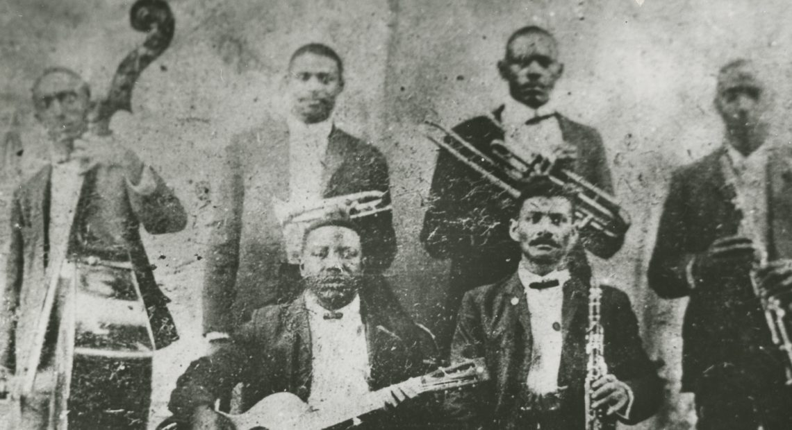 The only known photograph of Buddy Bolden, standing back row and second from left, horn in hand. Also pictured: guitarist Brock Mumford, bassist Jimmie Johnson, clarinetists Willie Warner and Frank Lewis, and trombonist Willie Cornish. Courtesy of the New Orleans Jazz Museum