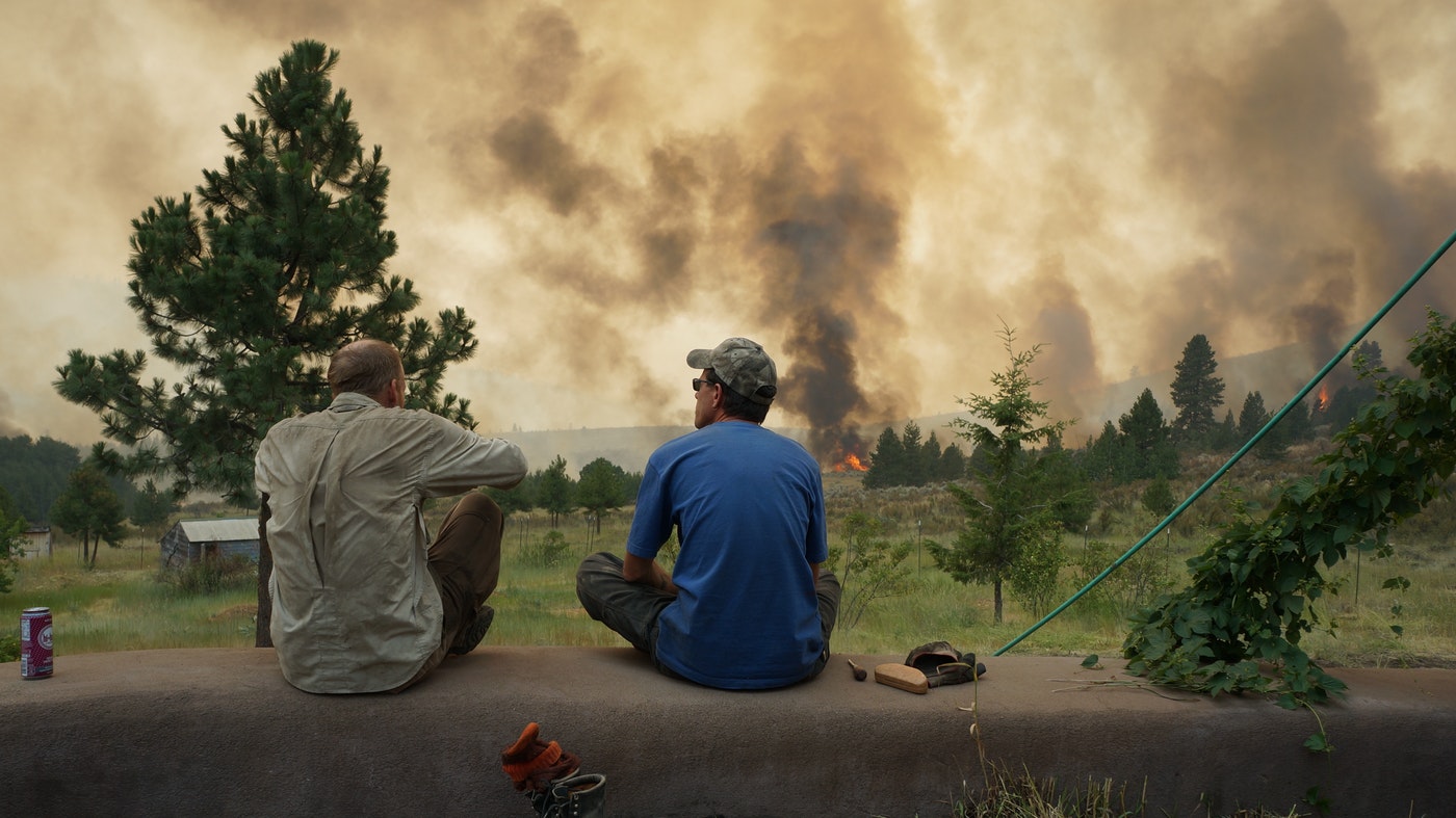 Twig Wheeler (left) and his friend Edward Glidden look out over the Carlton Complex fire from Wheeler's home outside of Carlton, Washington. CREDIT: COURTESY OF TWIG WHEELER