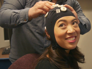 NPR's Elise Hu wears a cap that connects her to a network of other people playing a Tetris-like game at the University of Washington's Center for Neurotechnology.