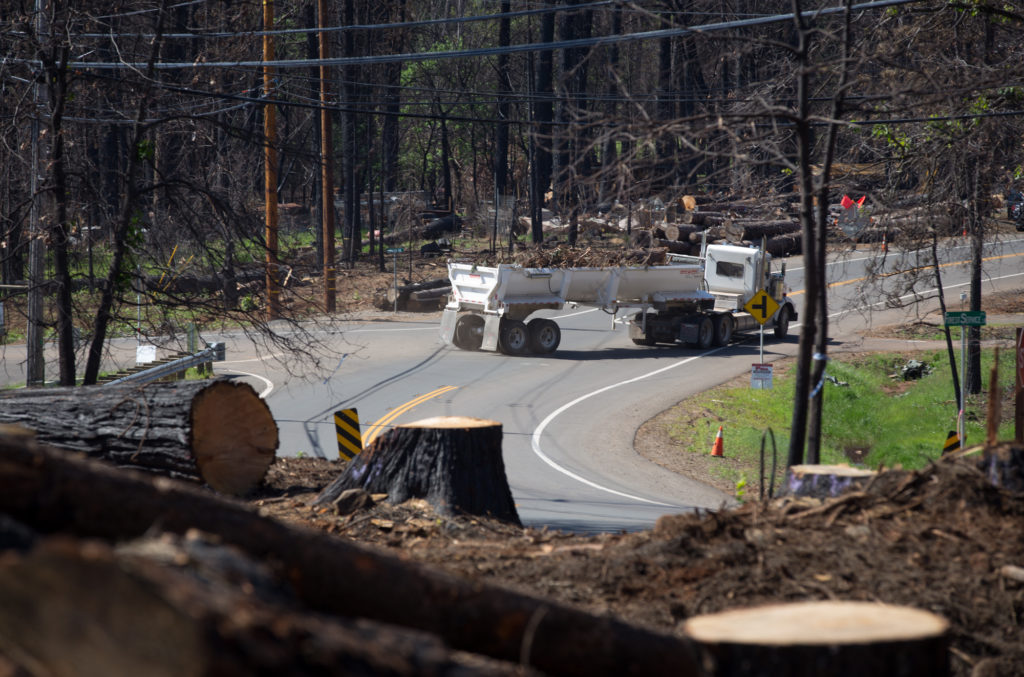 In April, trucks carry tree debris down Clark Road in Paradise, which was heavily forested before the fire. CREDIT: MEREDITH RIZZO/NPR