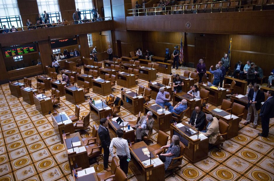 Democratic members of the Oregon Senate stand in the mostly empty Senate chambers at the Oregon Capitol in Salem, Ore., on Thursday, June 27, 2019. On the eighth day of a walkout by Republican senators, Oregon Senate President Peter Courtney adjourned the session shortly after it began due lacking the required number of senators to meet a quorum.