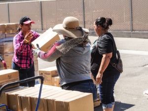 Volunteers and paid staff unload boxes of cheese, bread and rice for needy people in Heber, many of them elderly. CREDIT: JIM ZARROLI/NPR