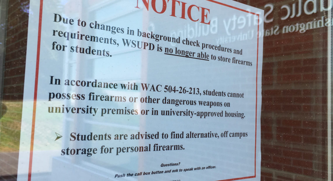 Reflecting on the glass door of the WSU Public Safety Building, a sign on the door announces the gun storage policy change Aug. 14, 2019. CREDIT: SCOTT LEADINGHAM/NWPB
