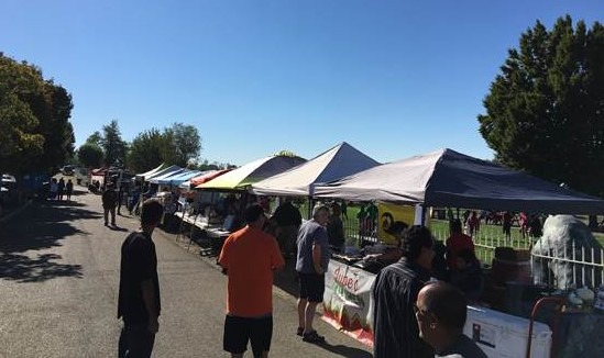 People walking around vendors under canopies at the Granger Menudo Festival.