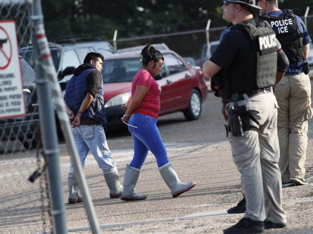 Two people are taken into custody by ICE agents at a Koch Foods Inc. plant in Morton, Miss., one of seven food processing plants targeted for coordinated raids in the state. CREDIT: Rogelio V. Solis/AP