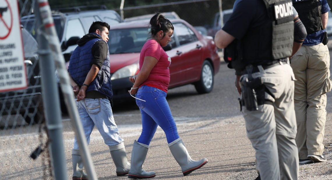 Two people are taken into custody by ICE agents at a Koch Foods Inc. plant in Morton, Miss., one of seven food processing plants targeted for coordinated raids in the state. CREDIT: Rogelio V. Solis/AP