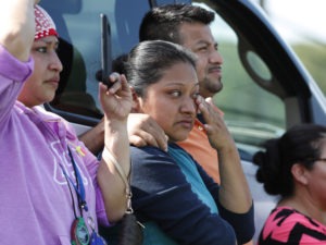 Friends, co-workers and family watch as U.S. immigration officials raid the Koch Foods Inc. plant in Morton, Miss., on Aug. 7, 2019. CREDIT: Rogelio V. Solis/AP