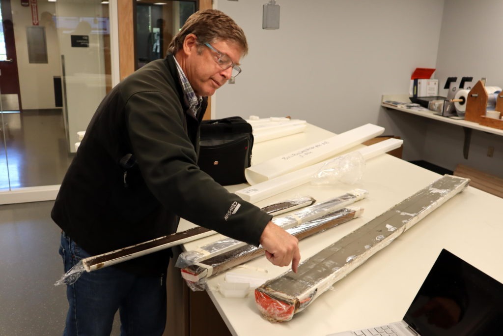 OSU marine geologist Chris Goldfinger shows an offshore sediment core, fat tube on right, and skinnier cores from Pacific Northwest lake bottoms, all of which contain traces of ancient earthquakes. CREDIT: TOM BANSE/N3