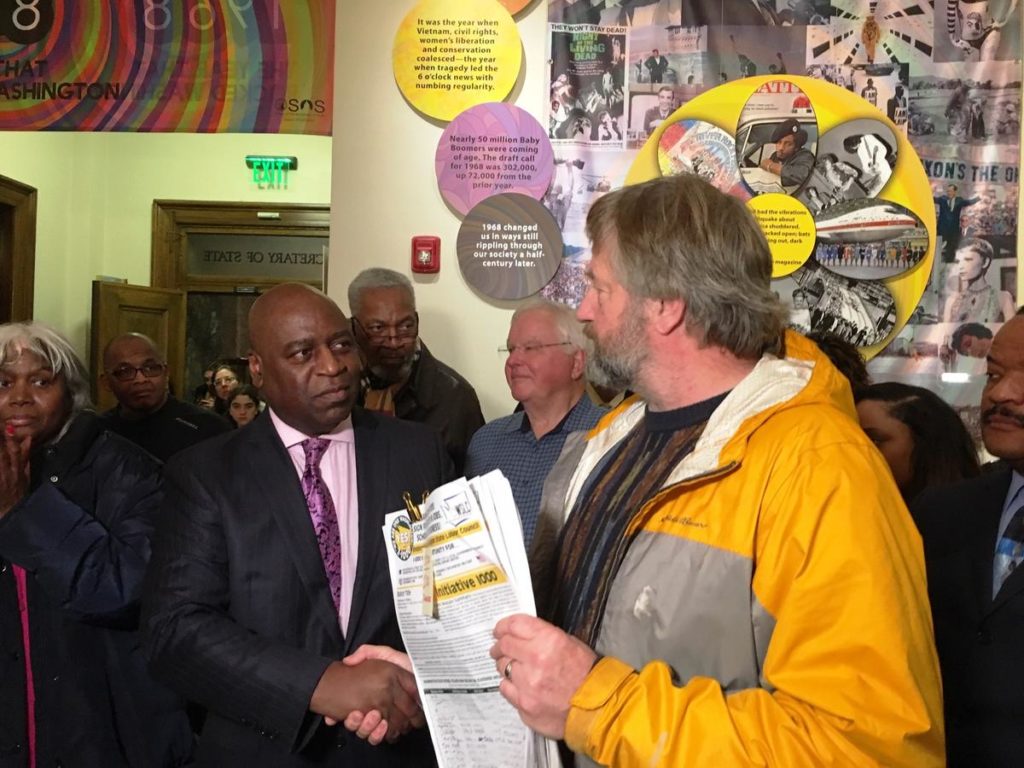 Roy Ruffino, right, of Citizen Solutions shakes hands with Jesse Wineberry of the I-1000 campaign at a petition drop-off event at the Secretary of State's office on Jan. 4, 2019. CREDIT: AUSTIN JENKINS / N3