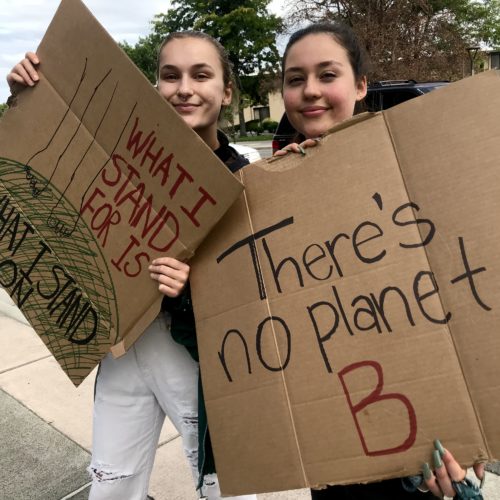 Alexandra Sasha Grieb and Kyleigh Dabler, both 19, from Kennewick, waved at passing cars driving by Richland’s John Dam Plaza. Grieb said it will be up to younger generations to fight climate change now with their votes. “The earth will survive climate change. Humans won’t,” she said. CREDIT: Courtney Flatt/NWPB