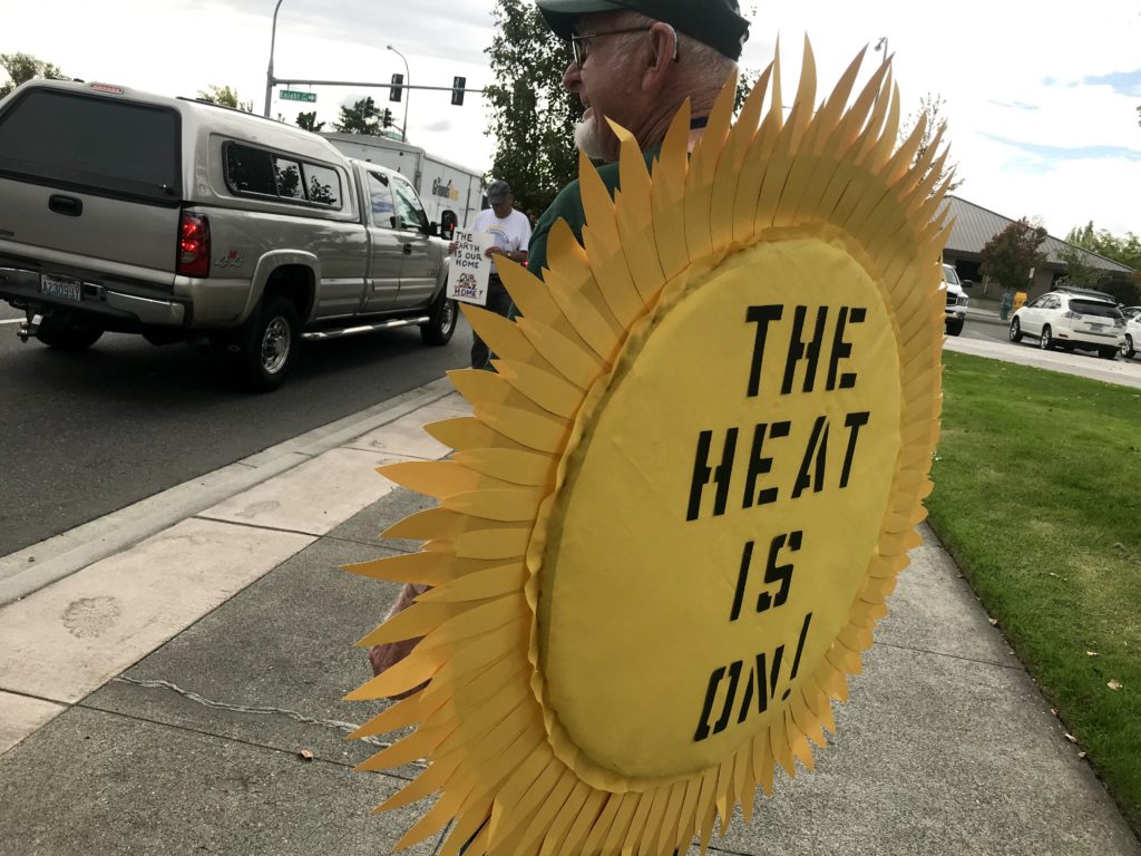 Frank Lockwood marched up and down one of Richland’s main thoroughfares wearing a sun sign that read, “The Heat Is On!” Around 40 protestors showed up for the hour-long event. CREDIT: Courtney Flatt/NWPB