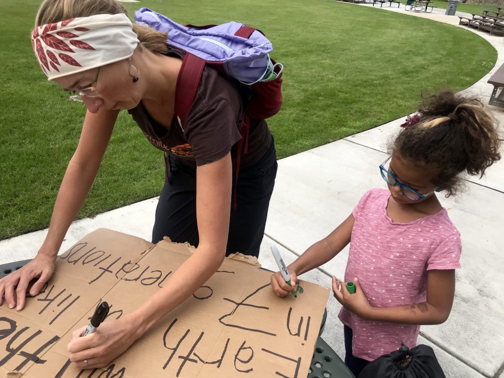 Noelle and Coa Hubbs decorate signs in Richland’s John Dam Plaza. Some people honked, waved or threw peace signs as they drove by the plaza. CREDIT: Courtney Flatt/NWPB