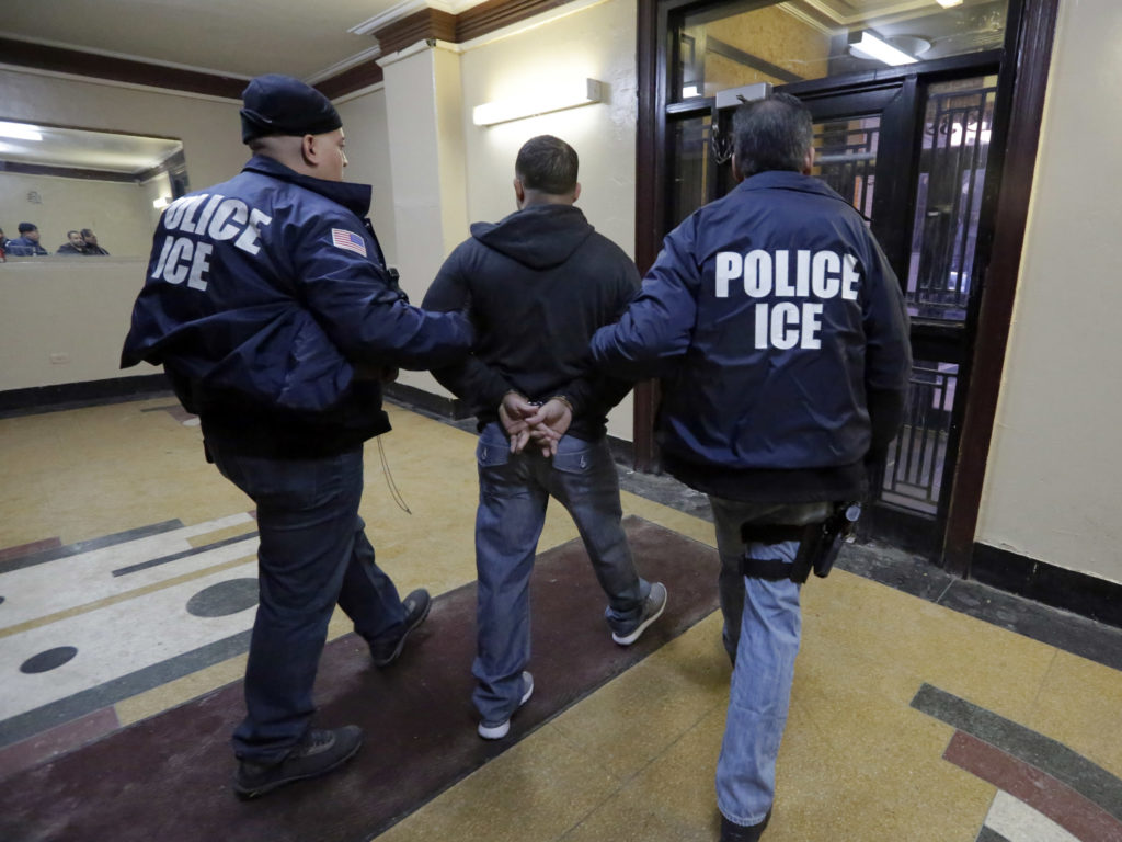 In this March 3, 2015, photo, Immigration and Customs Enforcement officers escort an arrestee in an apartment building in the Bronx borough of New York during a series of early morning raids. Richard Drew/AP