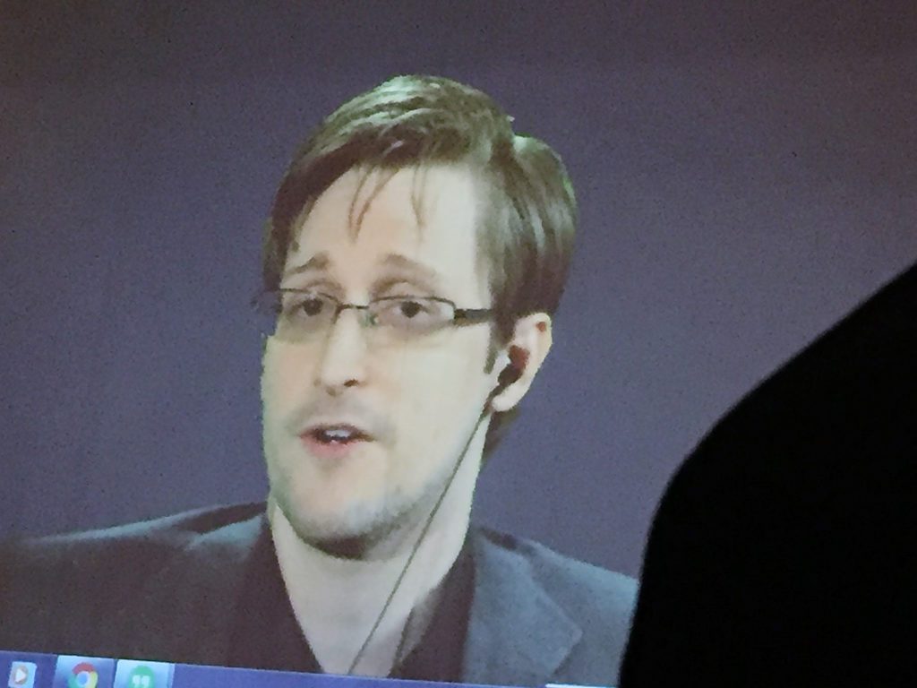 The Justice Department says Edward Snowden, seen here via video feed, breached nondisclosure agreements he signed with the National Security Agency and CIA with the publication of his new memoir, Permanent Record. Juliet Linderman /AP