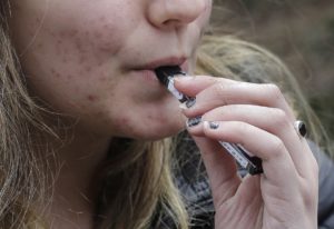 In this April 11, 2018 file photo, a high school student uses a vaping device near a school campus in Cambridge, Mass. CREDIT: STEVEN SENNE/AP
