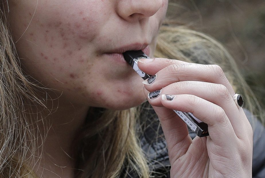 In this April 11, 2018 file photo, a high school student uses a vaping device near a school campus in Cambridge, Mass. CREDIT: STEVEN SENNE/AP