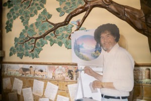 A life size cut out of Bob Ross stands up against the wall where the historical tree of the Franklin Park Arts Center is painted. Bob Ross Inc. is located in Herndon, Va., which is only 27 miles from the exhibit. According to managing director, Elizabeth Bracey, the exhibit was intentionally kept close to headquarters.