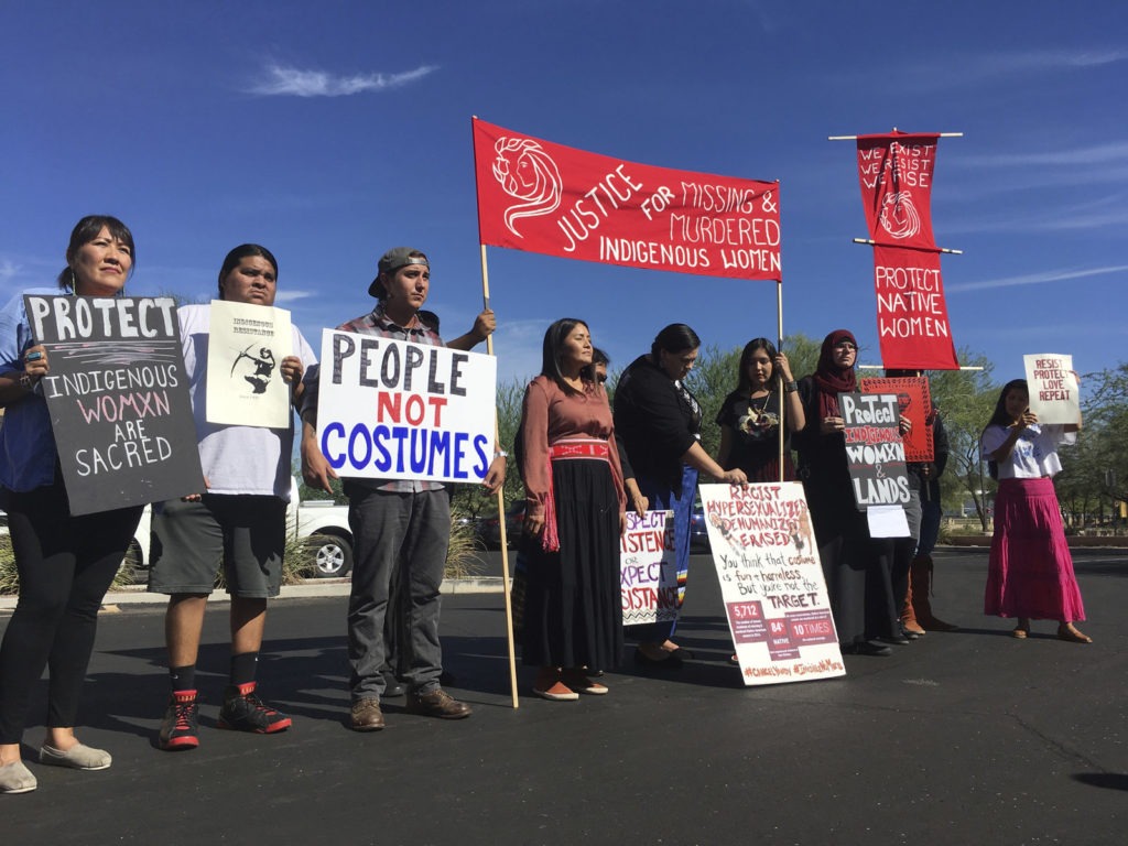 Native American protesters stand outside the Phoenix office of a retailer of "sexy Native American" costumes last year. For some ethnic and racial groups, Halloween has long been haunted by costumes that perpetuate stereotypes and instances of cultural appropriation. Terry Tang/AP