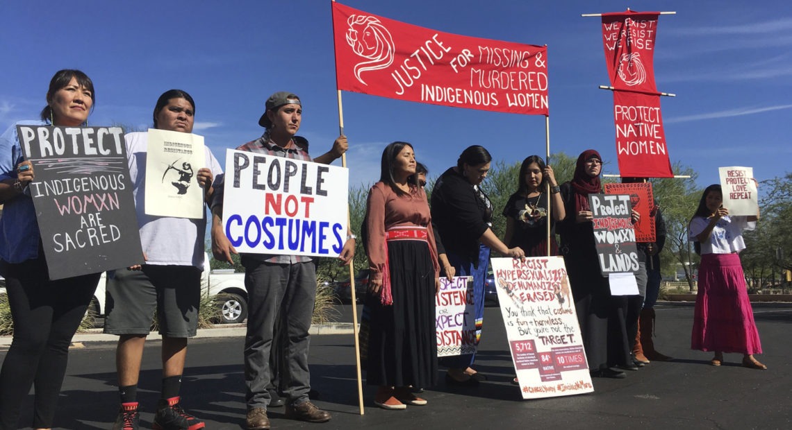 Native American protesters stand outside the Phoenix office of a retailer of "sexy Native American" costumes last year. For some ethnic and racial groups, Halloween has long been haunted by costumes that perpetuate stereotypes and instances of cultural appropriation. Terry Tang/AP