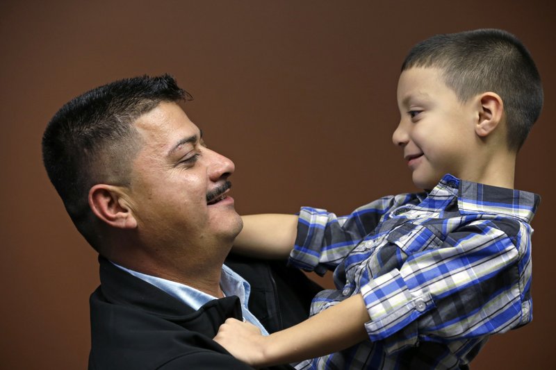 In this Oct. 17, 2014, file photo, Ignacio Lanuza holds his son, Isaiah, 4, as he has his photo taken in Seattle. A federal judge on Tuesday, Oct. 29, 2019, criticized the Justice Department for seeking legal fees from Lanuza, a Mexican immigrant who was the victim of a forgery by a government lawyer. CREDIT: Elaine Thompson/AP