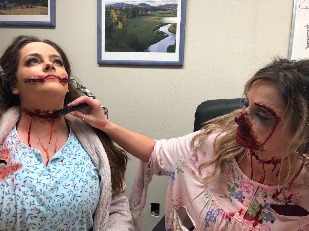 Megan Chandler of Clarkston, Washington, helps her friend Shelby Buttars add a bit more fake blood to her fake wounds in the city council chamber before going out to scare patrons of Haunted Palouse. They call themselves a “slumber party gone wrong.” They were putting on makeup in the city council chambers before going out to scare patrons at Haunted Palouse. CREDIT: Anna King/N3