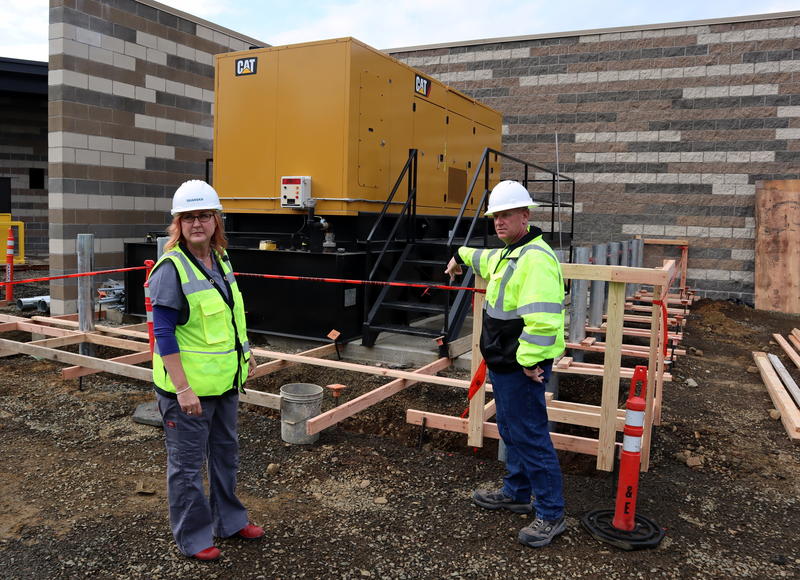 Dr. Lesley Ogden and Chris Lemar stand beside the backup generator at Lincoln City's new hospital, which is mounted on a shock-absorbing rack to protect against an earthquake.