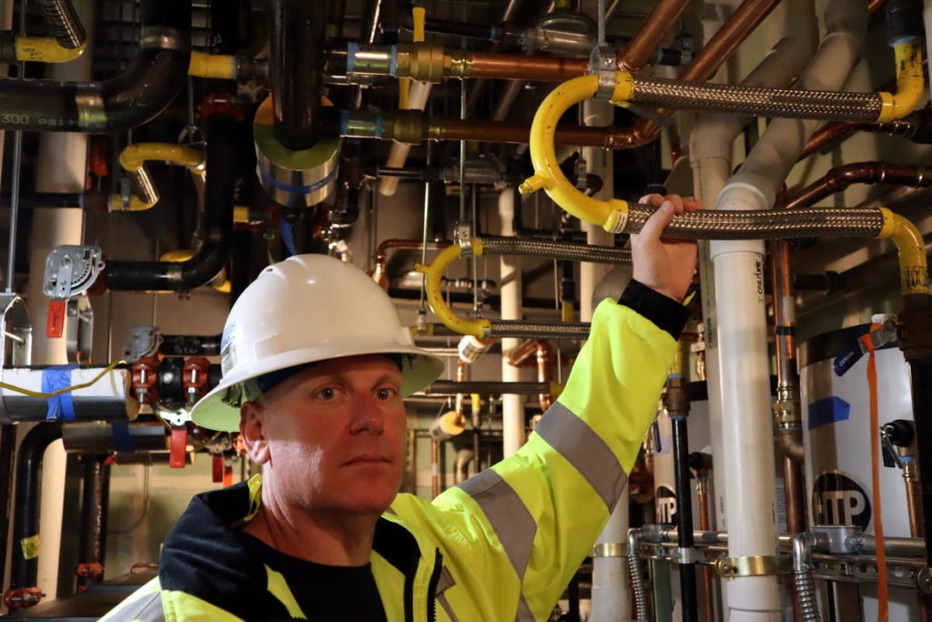 Samaritan North Lincoln Hospital facilities director Chris Lemar shows flexible piping designed to withstand earthquake shaking in the new hospital. CREDIT: Tom Banse/N3