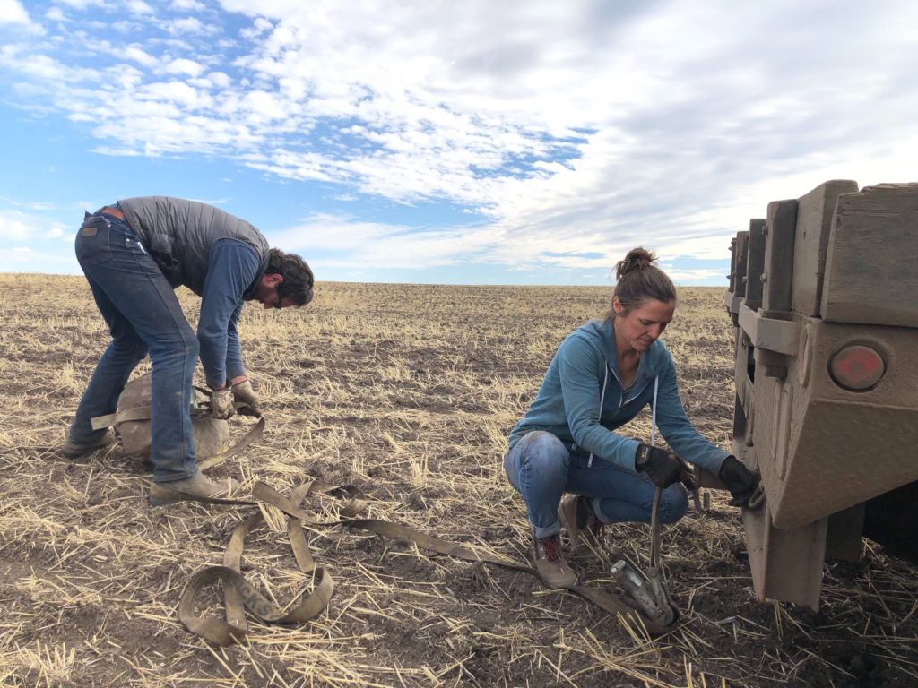 Erik Beottcher and Cori Wittman Stitt wrastle a large boulder to tow it out of a wheat field near Craigmont, Idaho. Relentless rain and an early snow have made harvest and now the planting of their winter wheat extremely tough. CREDIT: Anna King/N3