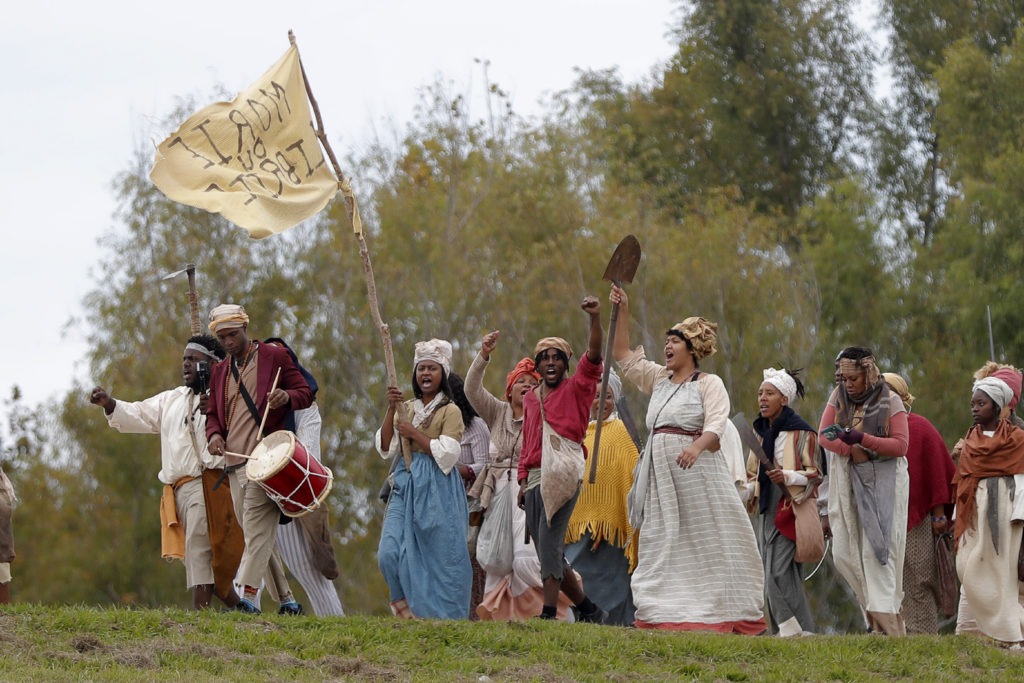 People march along the Mississippi River levee in Louisiana on Friday as they perform in a reenactment of the 1811 German Coast Uprising. Gerald Herbert/AP