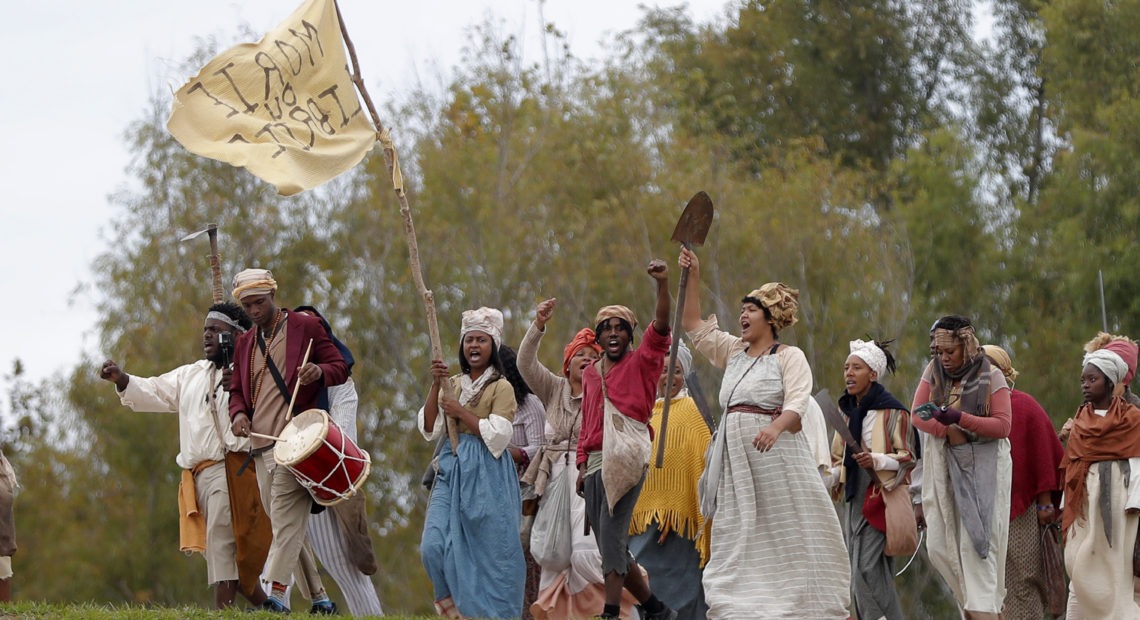 People march along the Mississippi River levee in Louisiana on Friday as they perform in a reenactment of the 1811 German Coast Uprising. Gerald Herbert/AP
