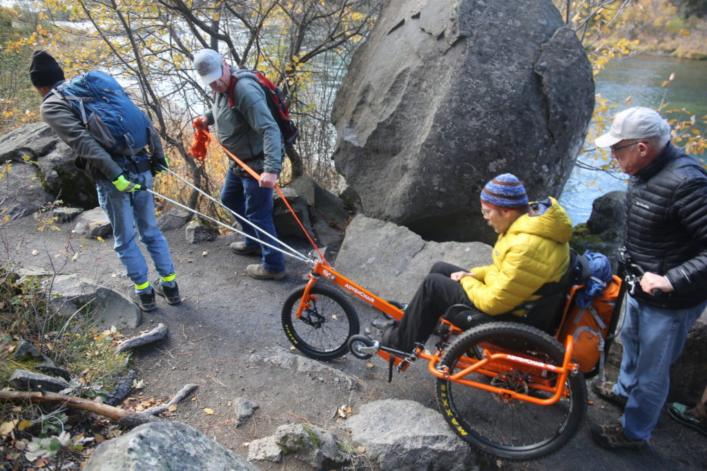 Geoff Babb's arms won't propel him, so he relies on teammates pushing, pulling and steering. CREDIT: Emily Cureton/OPB