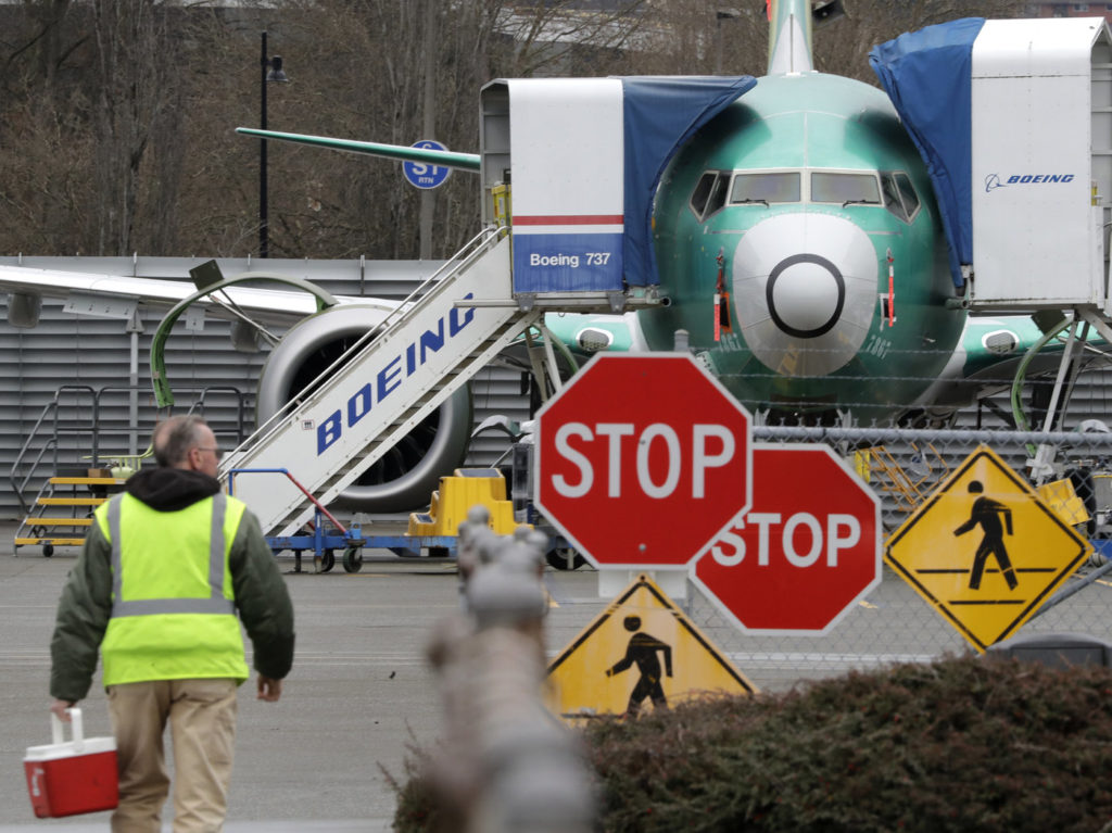 A Boeing worker walks near a 737 MAX jet on Monday in Renton, Wash. Boeing said it will suspend production of the troubled jetliner in January. Elaine Thompson/AP