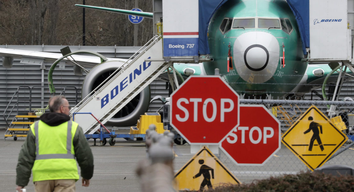 A Boeing worker walks near a 737 MAX jet on Monday in Renton, Wash. Boeing said it will suspend production of the troubled jetliner in January. Elaine Thompson/AP