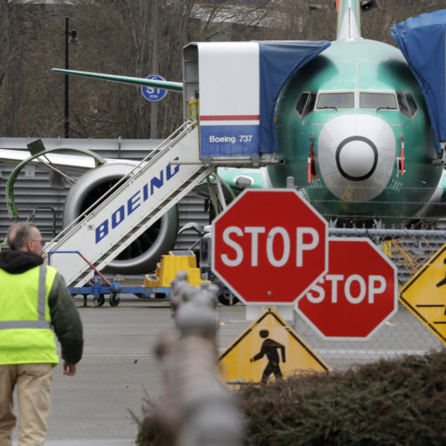 A Boeing worker walks near a 737 MAX jet on Monday in Renton, Wash. Boeing said it will suspend production of the troubled jetliner in January. Elaine Thompson/AP