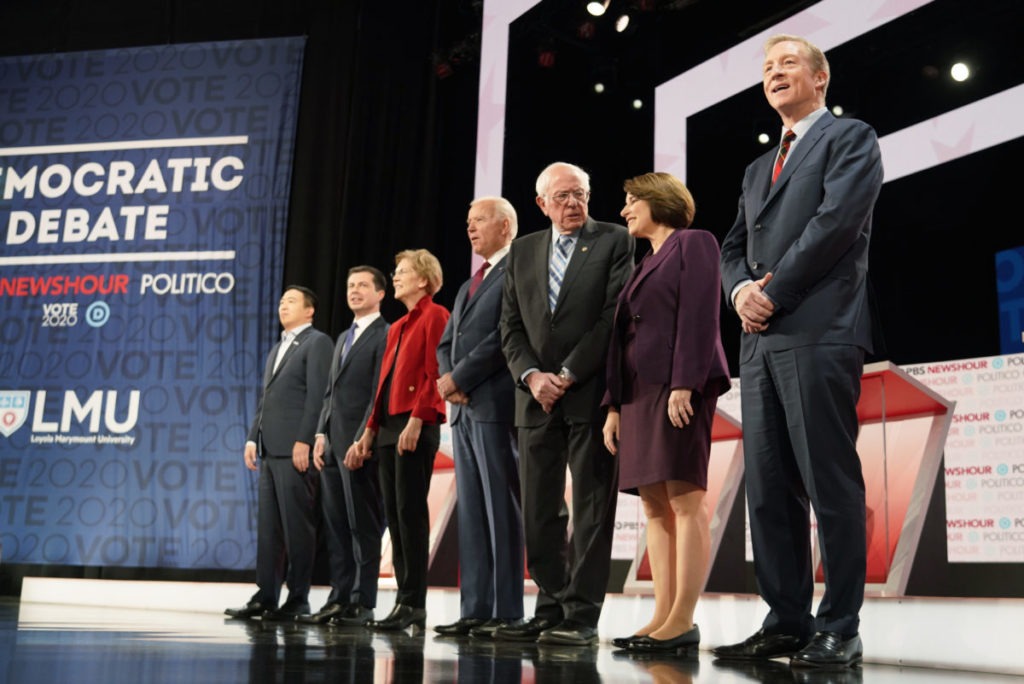 Democratic presidential candidates entrepreneur Andrew Yang, South Bend Mayor Pete Buttigieg, Senator Elizabeth Warren, former Vice President Joe Biden, Senator Bernie Sanders, Senator Amy Klobuchar and billionaire activist Tom Steyer take the stage for the sixth 2020 U.S. Democratic presidential candidates campaign debate at Loyola Marymount University in Los Angeles. CREDIT: PBS NewsHour