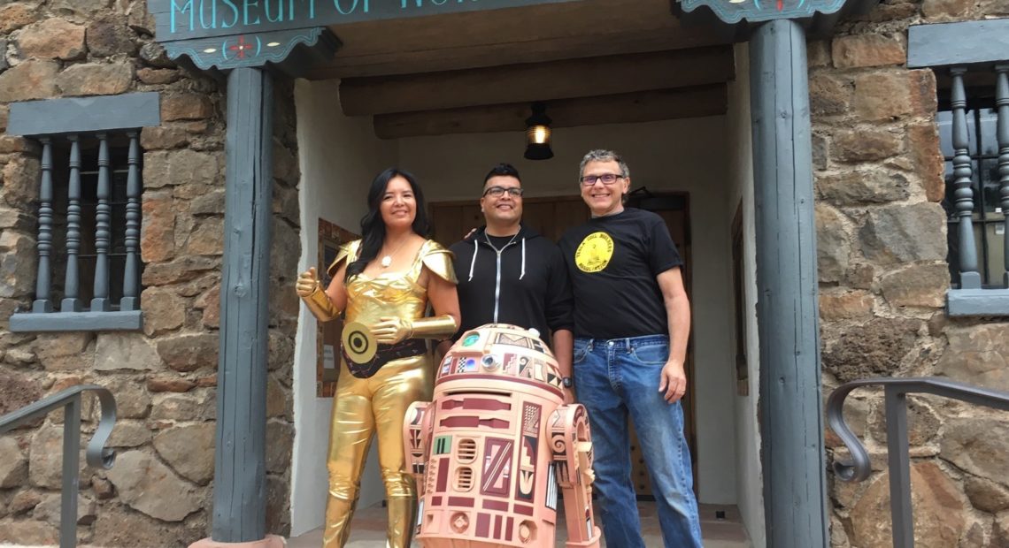 Geri Hongeva (left), who voiced C-3PO in the Navajo translation of A New Hope; artist Duane Koyawena (center); and engineer Joe Mastroianni with Hopi R2 at the Museum of Northern Arizona in Flagstaff. CREDIT: Ryan Heinsius/KNAU