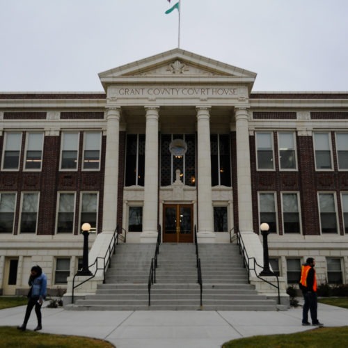 The Grant County Courthouse in Ephrata, pictured in November 2019, where federal immigration authorities have been spotted arresting undocumented people going to court since 2017. In front of the courthouse steps, Brenda Rodriguez with the Washington Immigrant Solidarity Network takes a phone call while a volunteer hands out “Know Your Rights” pamphlets. CREDIT: Enrique Pérez de la Rosa/NWPB