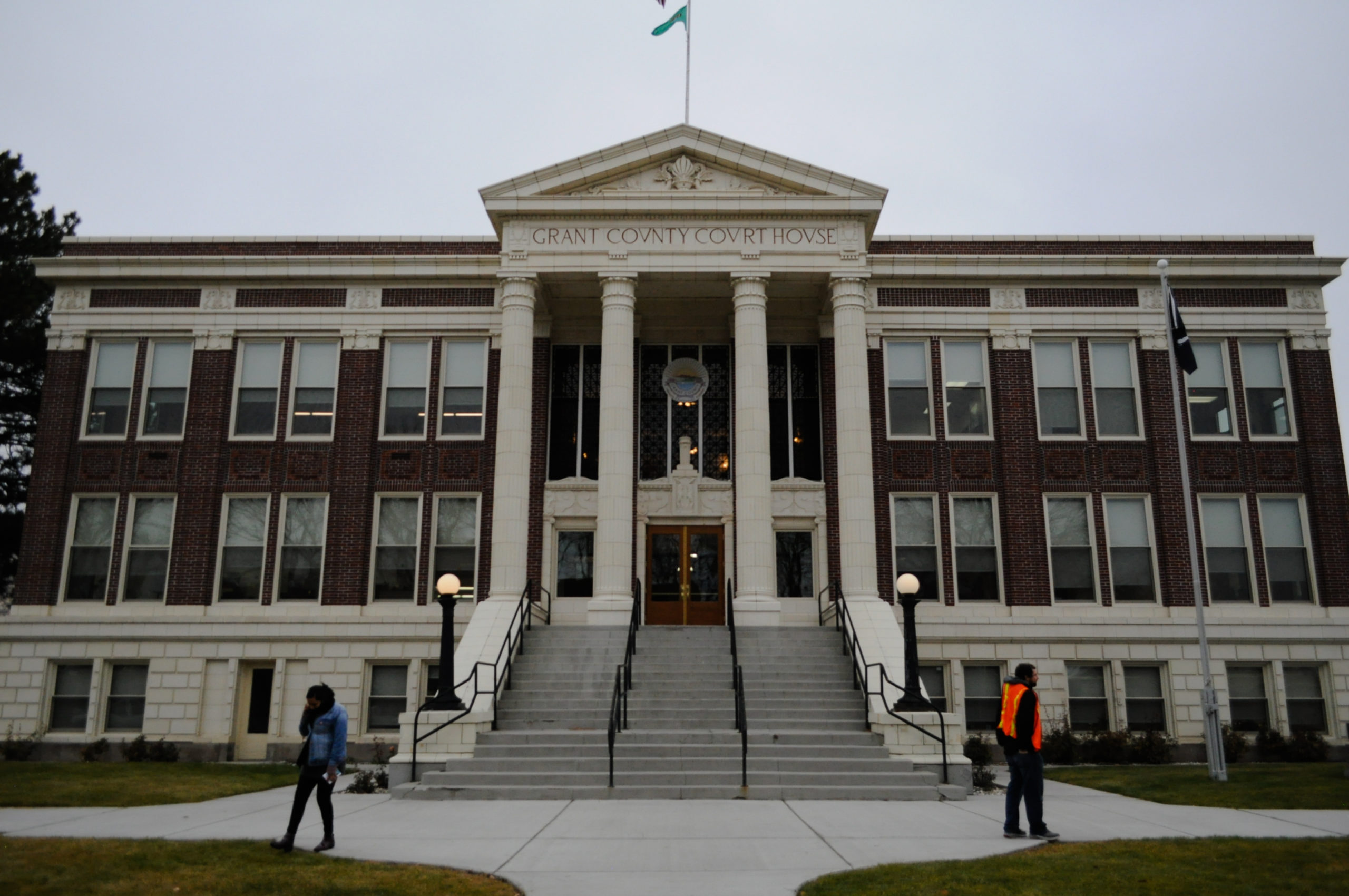 The Grant County Courthouse in Ephrata, pictured in November 2019, where federal immigration authorities have been spotted arresting undocumented people going to court since 2017. In front of the courthouse steps, Brenda Rodriguez with the Washington Immigrant Solidarity Network takes a phone call while a volunteer hands out “Know Your Rights” pamphlets. CREDIT: Enrique Pérez de la Rosa/NWPB